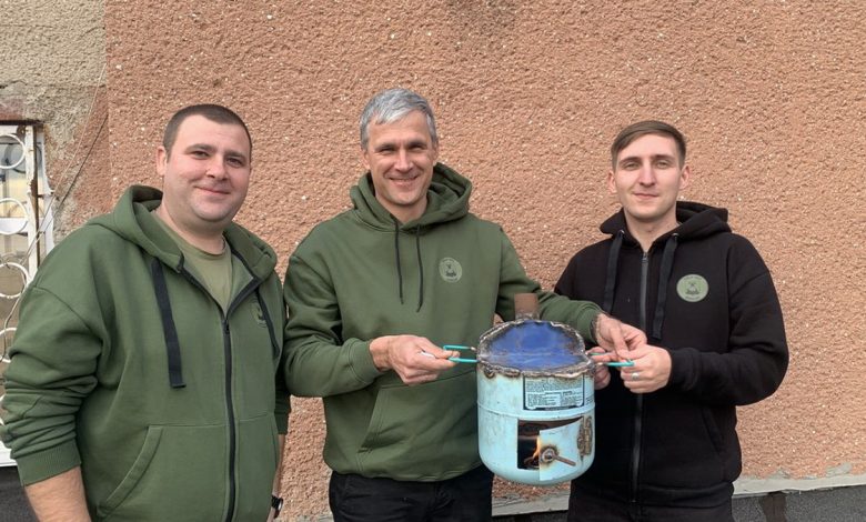 Волонтери тримають зроблену буржуйку для військових. Фото: Богдана Будулуца/Суспільне Миколаїв